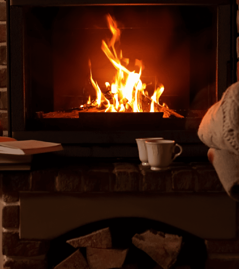 Cozy fireplace with warm woolen blanket and cup of hot drink<br />
